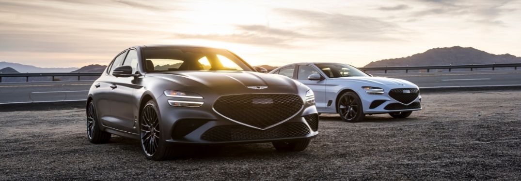 Gray and White 2022 Genesis G70 Models Next to a Highway at Sunrise