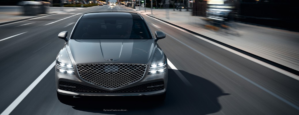 A front view of the 2022 Genesis G80 driving on the highway, with the background blurred to show motion