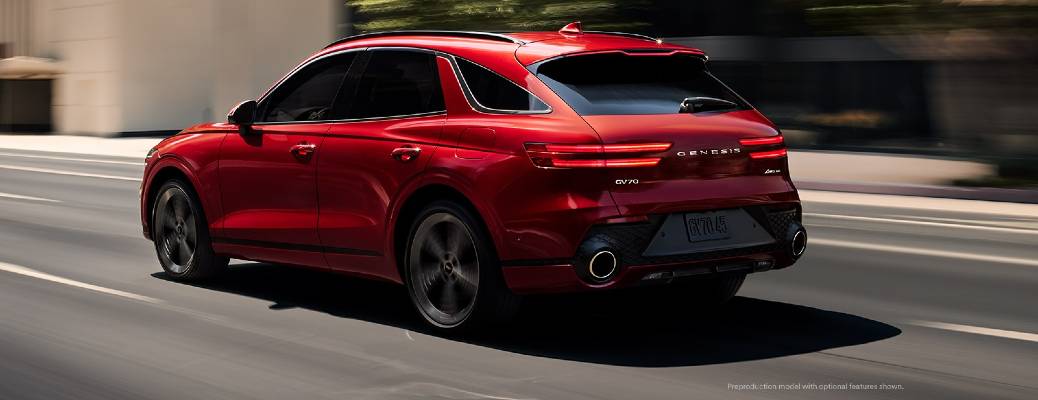 A red 2022 Genesis GV70 driving along an urban street, as seen from the rear in 3/4 view. Cover image for an article on How to Use the Genesis GV70 Digital Instrument Cluster