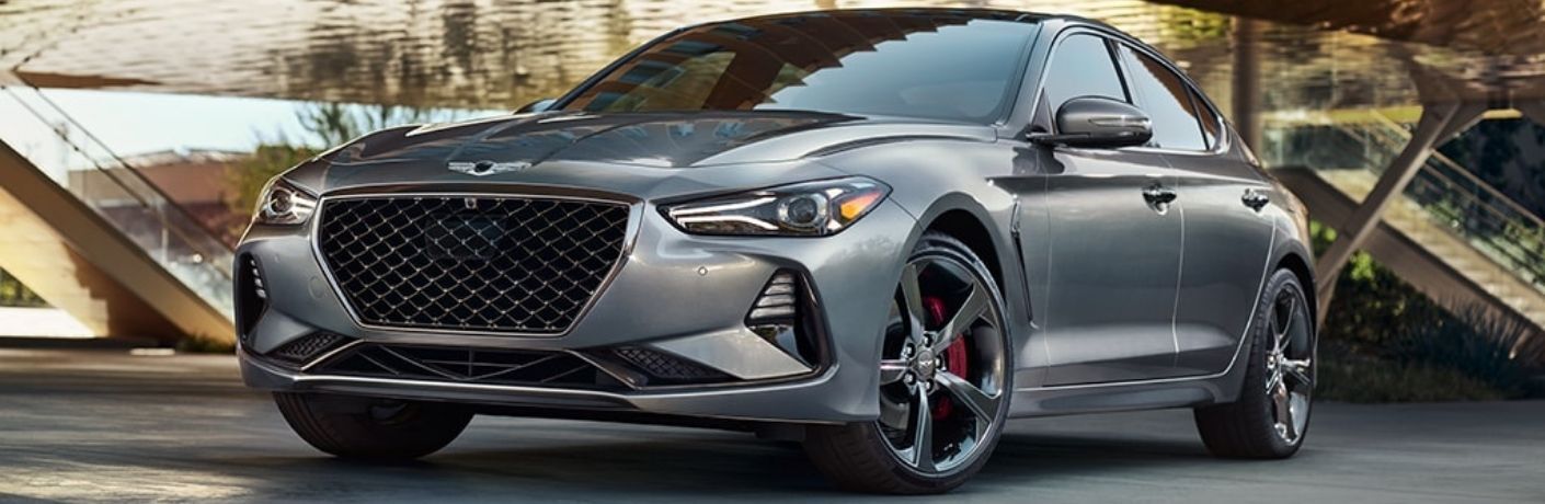Luxury silver sedan parked outdoors, featuring a sleek design, bold front grille, and alloy wheels