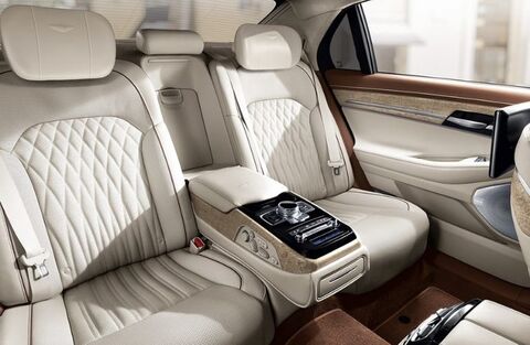 Rear passenger seats of a Genesis G90 with leather upholstery and a center console.