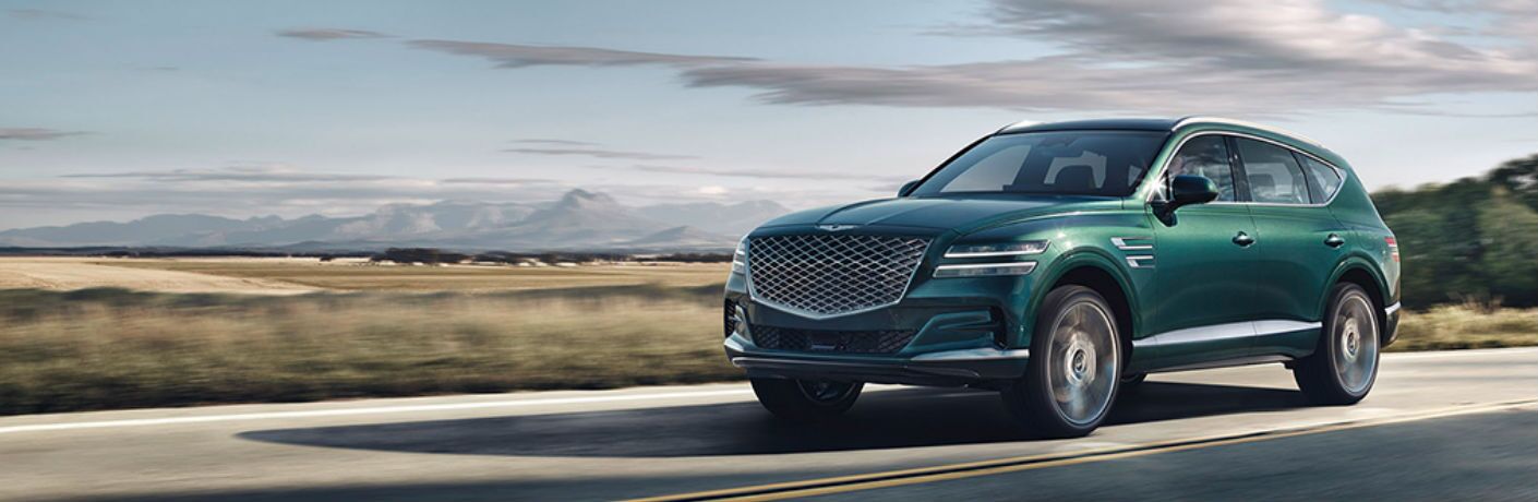 Genesis GV80 driving on a scenic road.