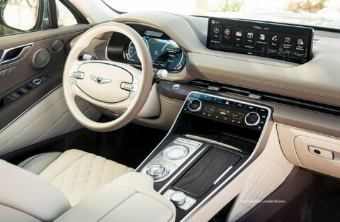 Genesis GV80 interior with a large touchscreen display and beige leather seats.