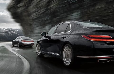 Genesis G90 driving on a winding road.