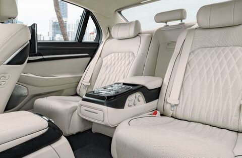 Rear passenger seats of a Genesis G90 with leather upholstery and a center console.