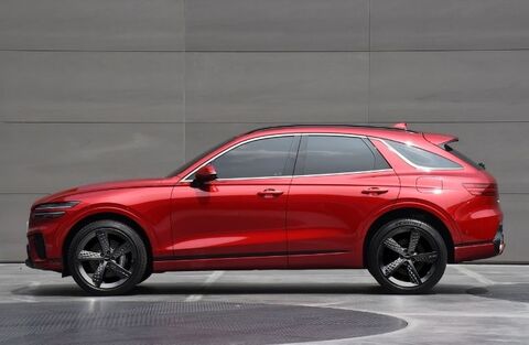 Side view of a red Genesis GV70 Shooting Brake parked in a studio.