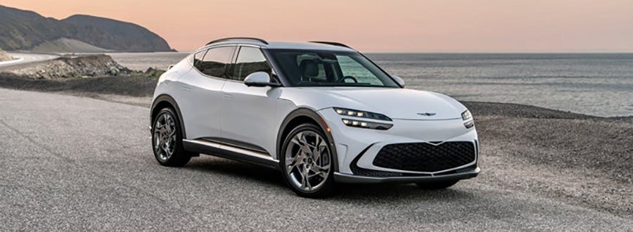 White Genesis GV60 parked on a cliff overlooking the ocean.