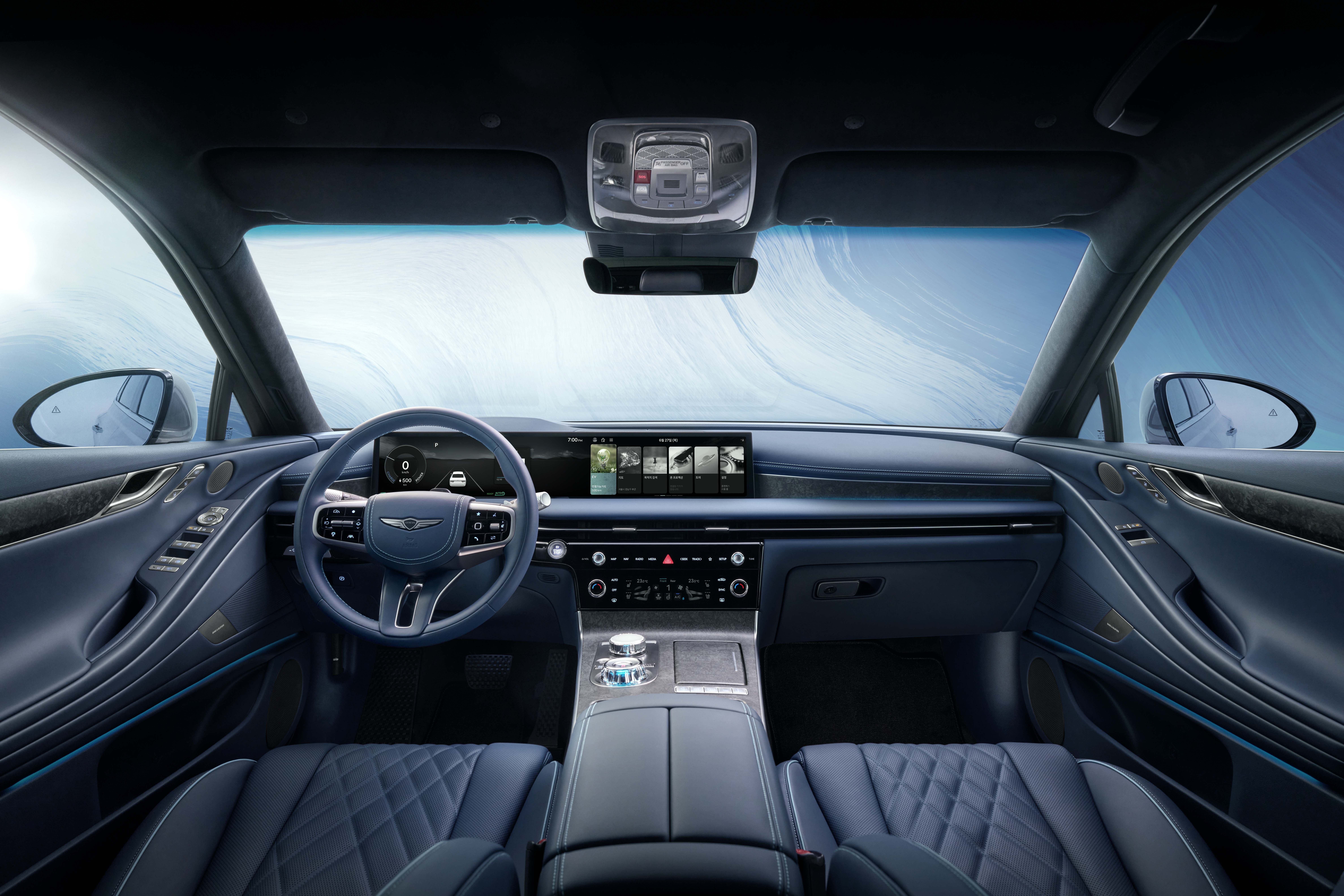 Interior view of a 2025 Genesis Electrified G80 showcasing its integrated digital display, blue leather steering wheel, detailed center console, and quilted blue leather seats, conveying modern luxury.