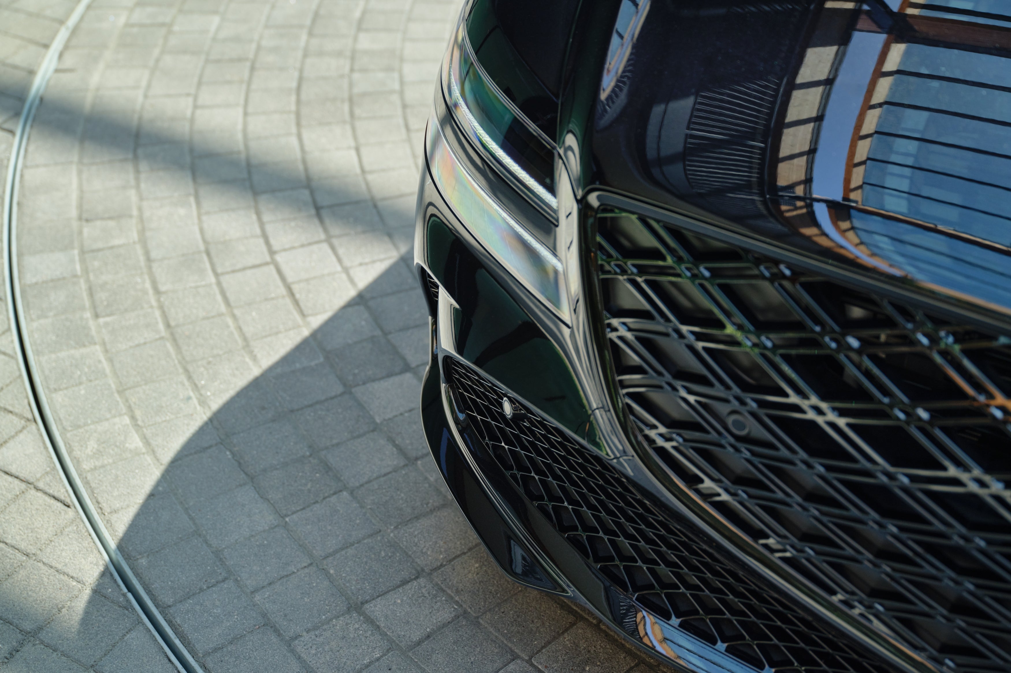 The hood, grill, and right headlight of a vik black 2026 G80 is seen from above.