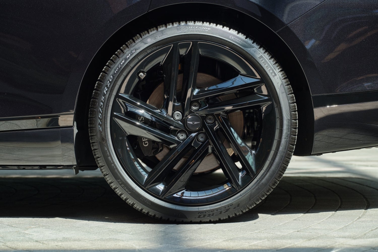 The back driver's side wheel of the new Genesis sedan is parked on pavement in Phoenix.