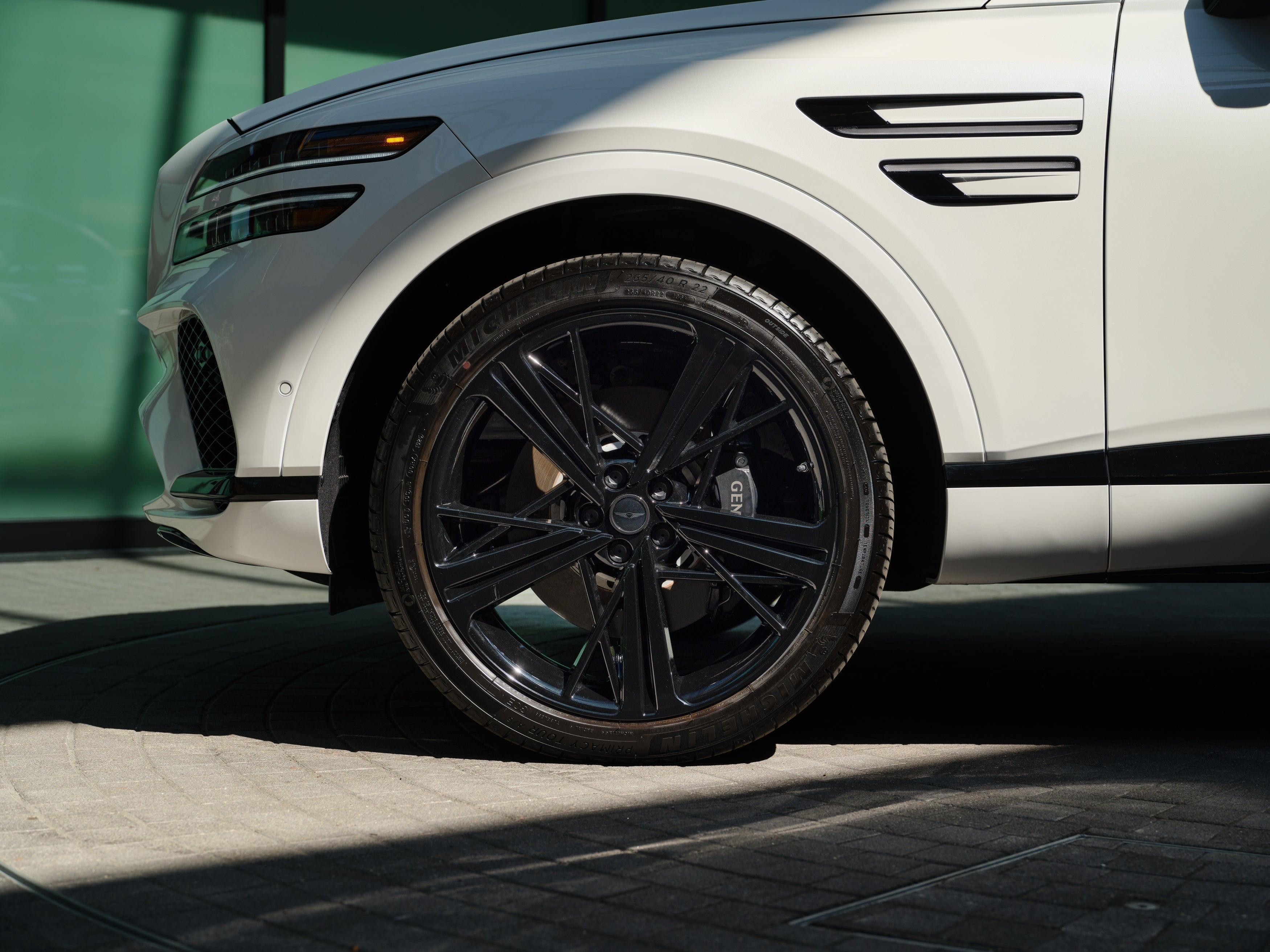 The front driver's side wheel of the 2026 Genesis GV80 Coupe is shown parked on pavement in Scottsdale.