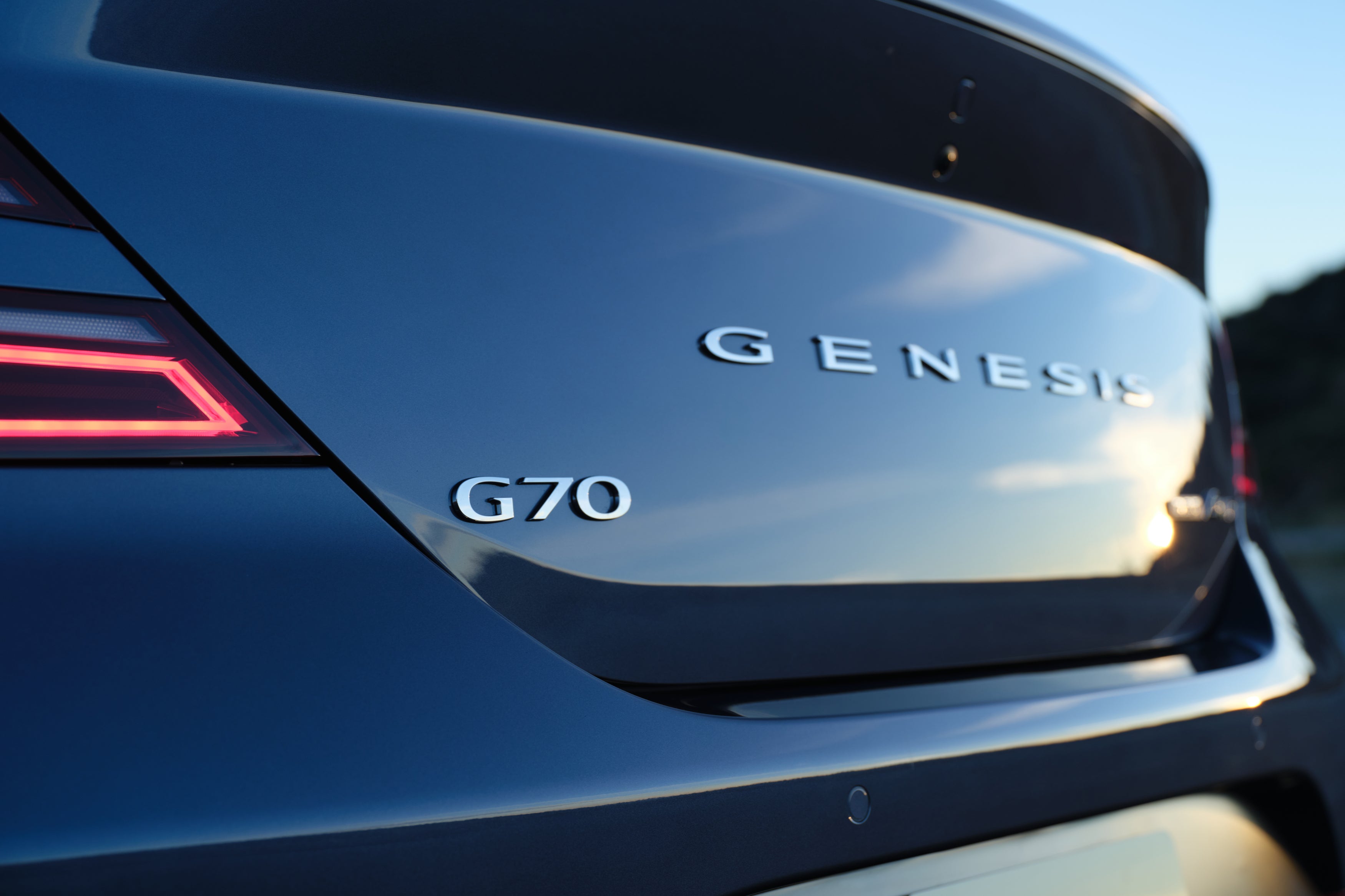 The Genesis name on the backside of a makalu gray 2026 Genesis G70 in Phoenix is seen up close from the left.