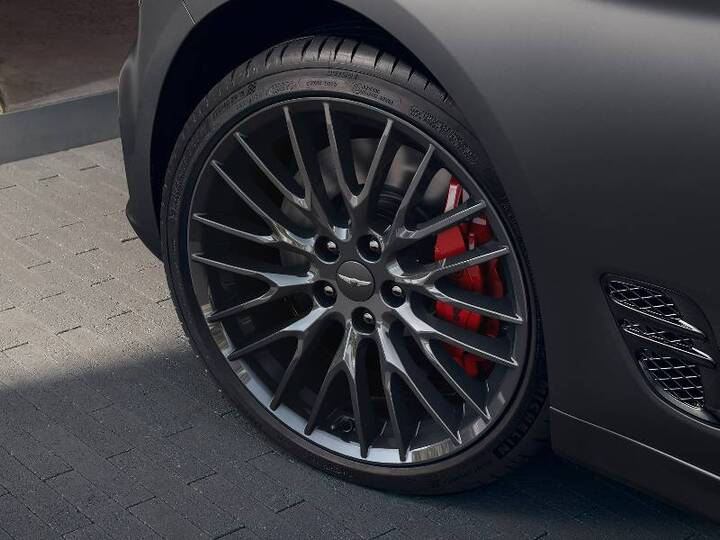 Black alloy wheel with red brake calipers on a Genesis G70.