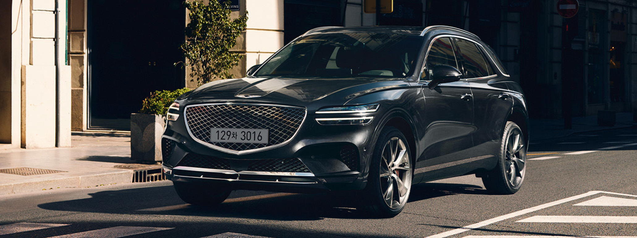 Genesis GV70 driving on a city street.