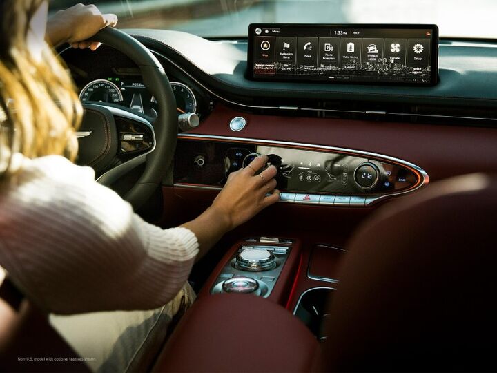A woman adjusts the controls of a Genesis GV70 with a large touchscreen display.