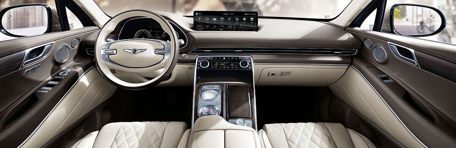 Genesis GV80 interior with a large touchscreen display and beige leather seats.
