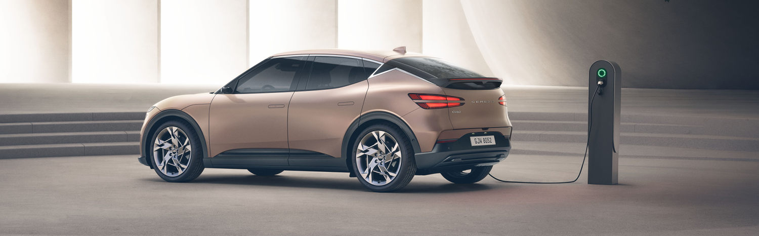 Rear view of a bronze Genesis X Convertible charging at an electric vehicle charging station.