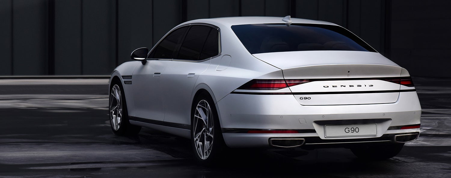 Rear view of a white Genesis G90 parked in front of a building.
