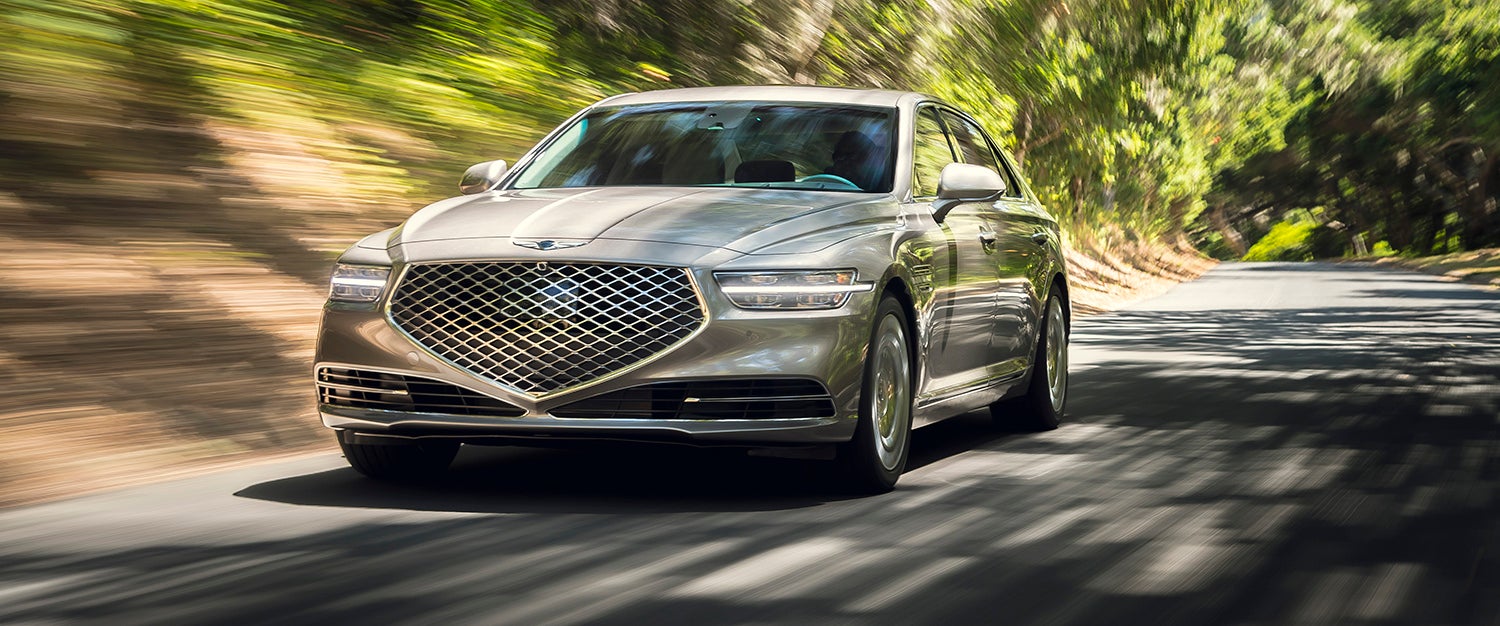 Rear view of a red Genesis G80 parked near the ocean.