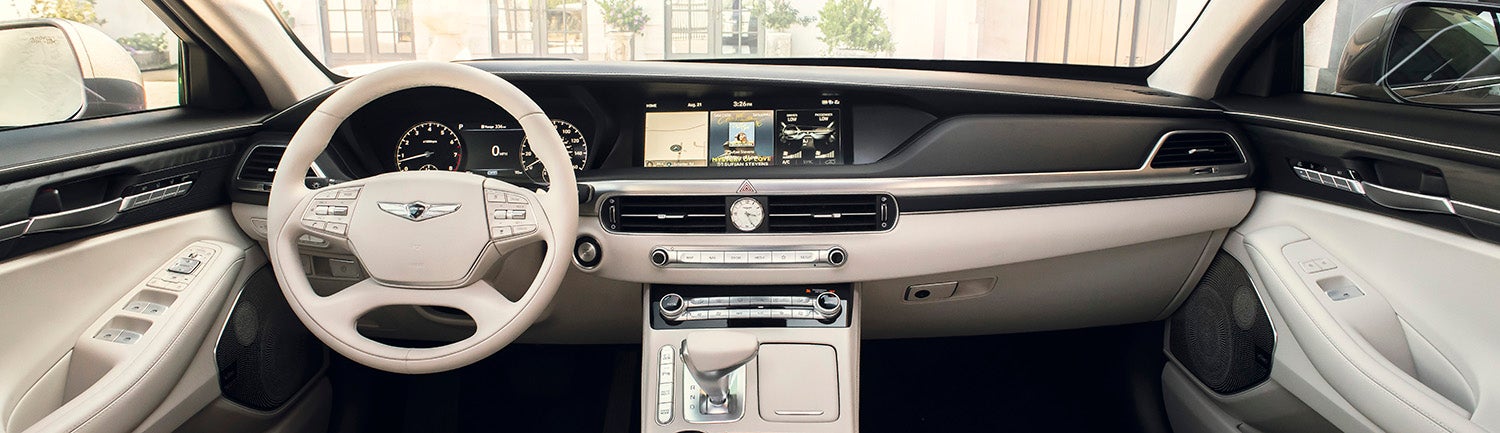 Genesis G90 interior with a large touchscreen display and beige leather seats.